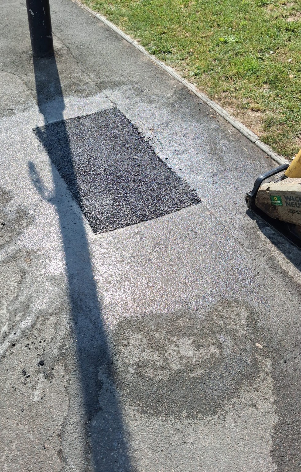 Tarmac patch repair beside a kerb